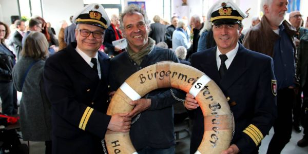 Jörn Hilgert (links) und Jörn Schwarz von der Wasserschutzpolizei übergaben Werner Pfeifer einen Rettungsring der Bürgermeister Brauer. Foto: cb Fischhalle