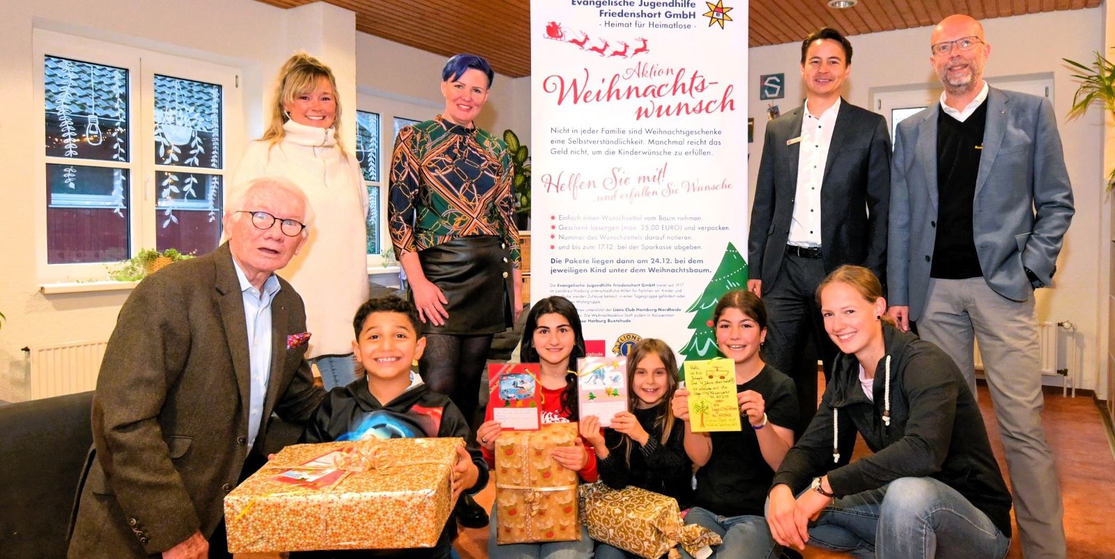 Gemeinsame Vorfreude auf den Startschuss der Aktion Weihnachtswunsch 2023:  Hinten v.l.: Sarah Fuhlbohm und Claudia Warnke (Jugendhilfe Friedenshort), Tim Beckmann (Sparkasse Harburg-Buxtehude), Thomas Wilde (Lions Club). Vorne v.l.: Bernd Baatz (Lions Club) sowie Mohamed, Yasemeen, Yvonne, Armeera, Jana Pluntke (Jugendhilfe Friedenshort). Foto: Sparkasse