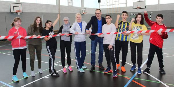 Die Schüler der Klasse 8T1 griffen am Montagmorgen gemeinsam mit Schulleiter Jörg Isenbeck und Sportlehrerin Bianca Weiterer-Berger zur Schere, um das Rote Band durchzuschneiden. Foto: Christian Bittcher Neubau für 1,45 Mio: FEG-Schüler nehmen Sporthalle in Beschlag