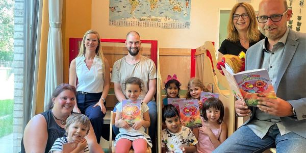 Autor Johannes „Jojo“ Tapken (rechts) gemeinsam mit Josefin Kühn (v.l.), Vorständin Natja Berg, Patrick Voss und Sandra Schmücker ließt Kindern aus der Kita Zauberwiese aus Vielfaltfantastisch vor. Foto: privat Tausendsassa „Jojo“ Tapken: Jetzt ist er auch noch Kinderbuchautor