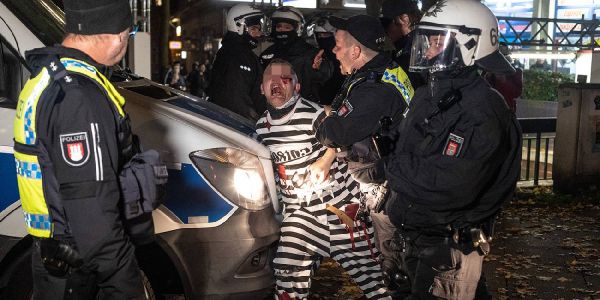 Polizisten haben einen jungen Mann, der sich als Sträfling verkleidet hatte, festgesetzt. Foto: André Zand-Vakili Halloweenkrawall