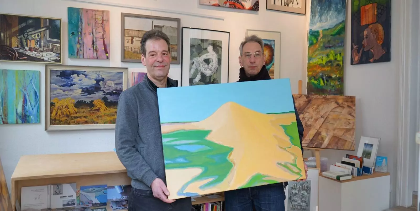 Künstler Jan Ratschat (rechts) schenkt zum 5jährigen Bestehen sein Werk „Große Düne“, Öl auf Leinwand, 2022, der Kunstleihe Harburg. Foto: S. Schnell