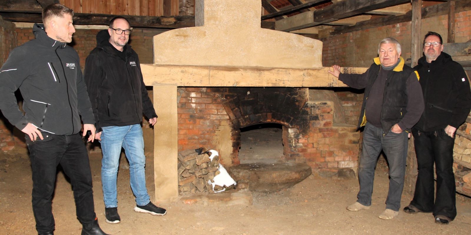 Der alte Backofen soll wieder brennen: Die Handwerker Jan Schleicher (von links) und Tino Niess von Brawa Nord, Eigentümer Achim Peters und Zimmermeister Marco Matthies freuen sich über die gelungene Sanierung des alten Backhauses. Foto: Landkreis Harburg