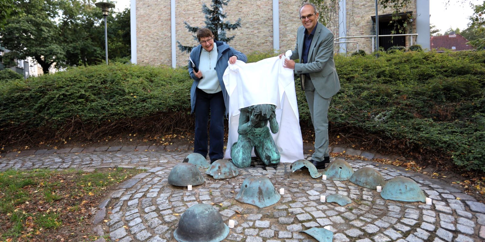 Pastorin Sabine Kaiser-Reis und Bezirksamtsleiter Christian Carstensen enthüllen die restaurierte Skulptur. Foto: Christian Bittcher